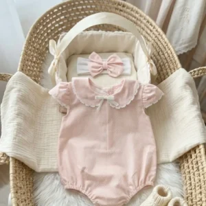 Ranita Primera Puesta rosa de bebé con cuello babero y diadema a juego sobre moisés de mimbre